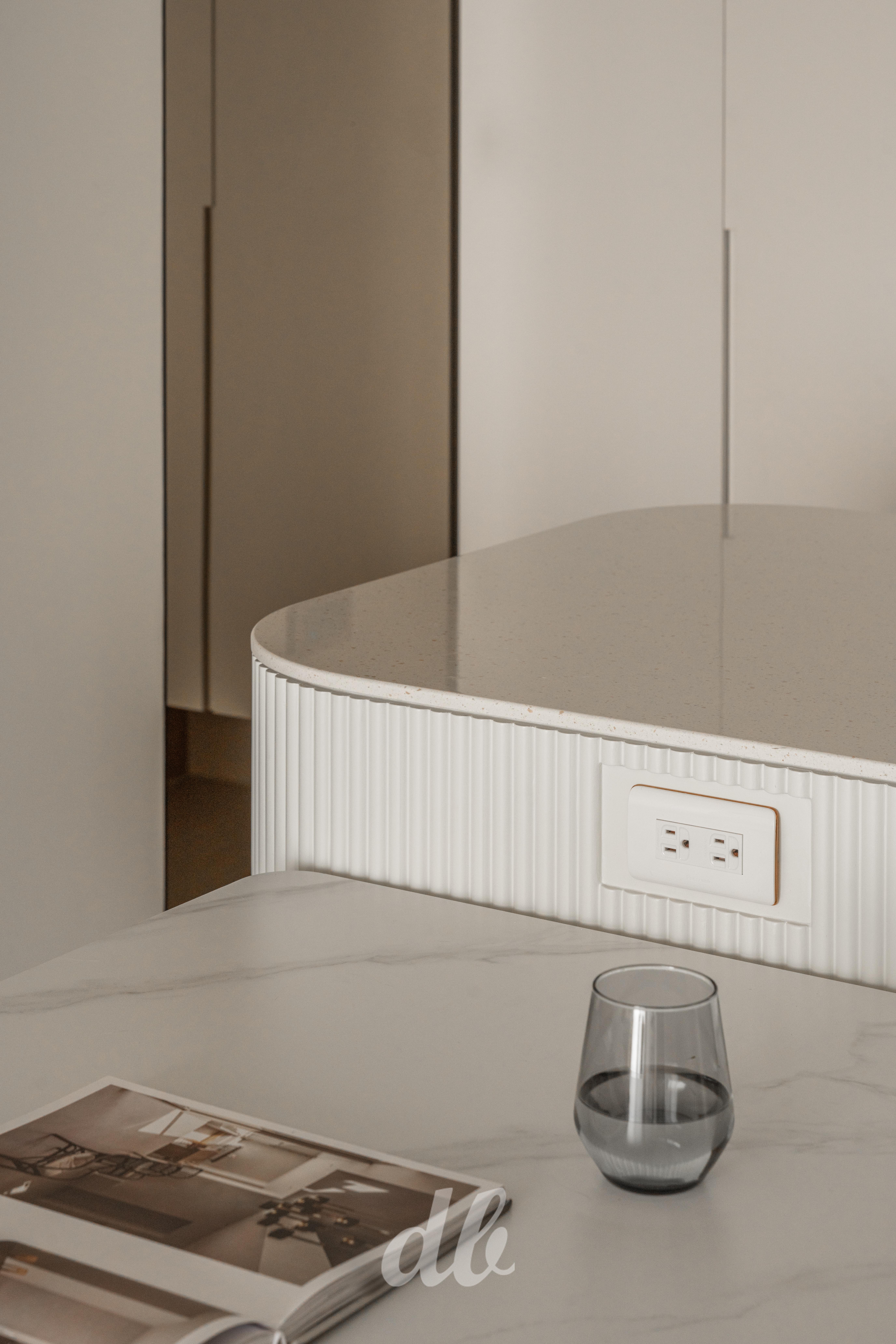 韓式奶油風細節美學：中島吧台採用細緻白色造型格柵設計，搭配耐看的大理石紋餐桌，透過圓潤線條消弭稜角感，展現出奶油色系空間中異材質拼接的優雅層次。