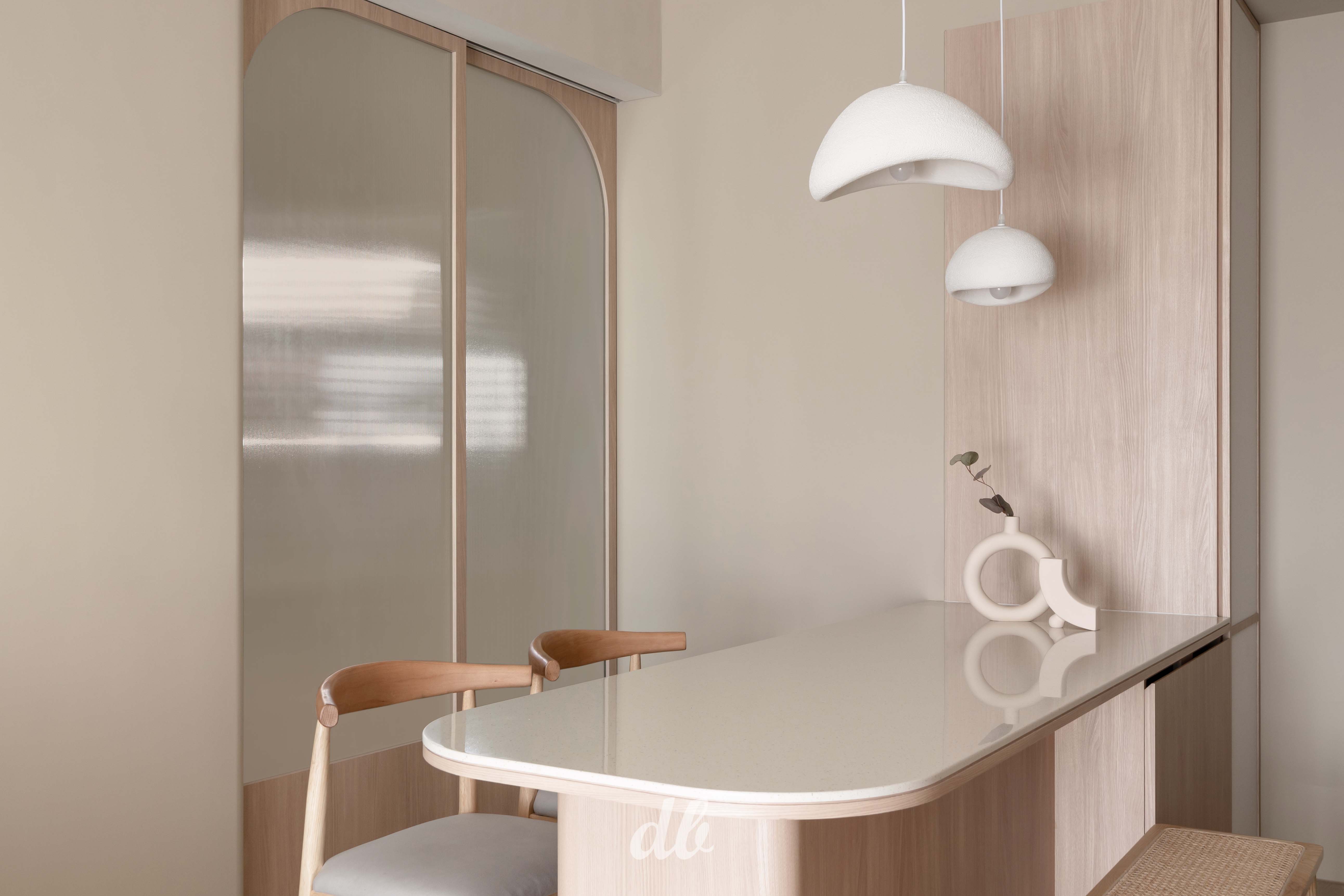 韓式奶油風餐廳空間（日造設計案例）：圓弧造型的淺木質餐桌與長虹玻璃推拉門，搭配質感溫潤的白色造型吊燈，透過流暢的弧形線條與暖米色調，營造出充滿層次感且優雅的韓系簡約日常氛圍。