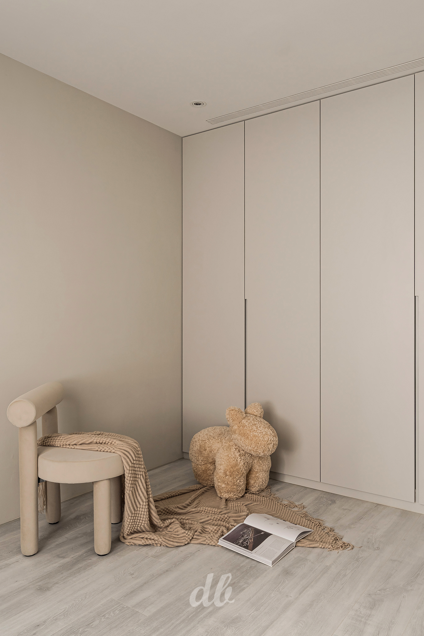 韓式奶油風兒童房/角落設計：運用高明度的暖米色牆面與同色系平整衣櫃，搭配造型圓潤的布藝單椅與可愛的動物造型凳，並鋪設異材質針織毯以疊加視覺層次，營造出簡潔、溫潤且充滿童趣的居家氛圍。