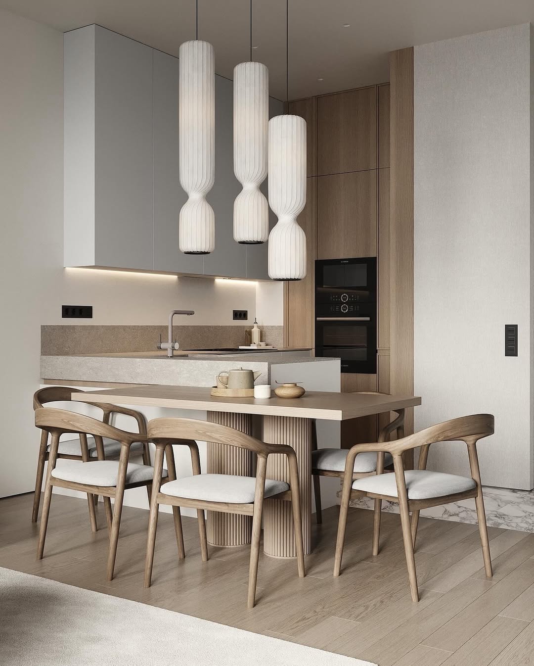 L型中島設計案例：淺木質格柵圓柱餐桌銜接石材吧台，搭配原木編織餐椅與獨特的長型幾何風琴吊燈，在和諧的大地色系中營造出優雅且具藝廊質感的開放式用餐空間。